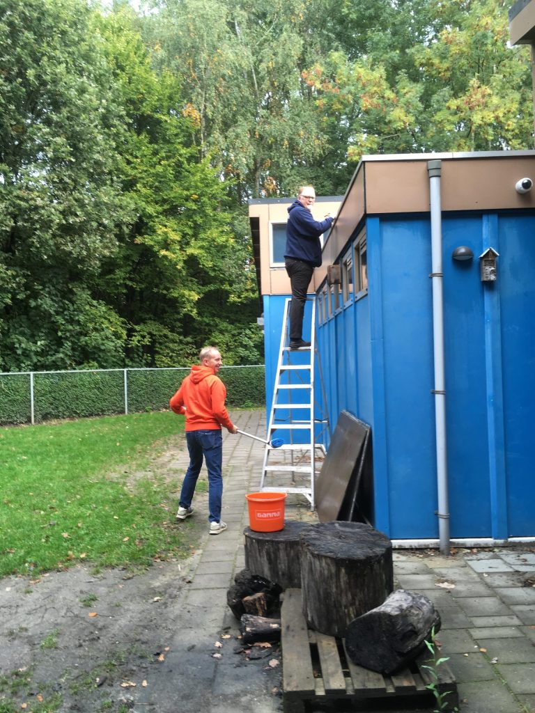 Het klusteam, wat voor een deel bestaat uit ouders, maakt de dakgoten schoon.